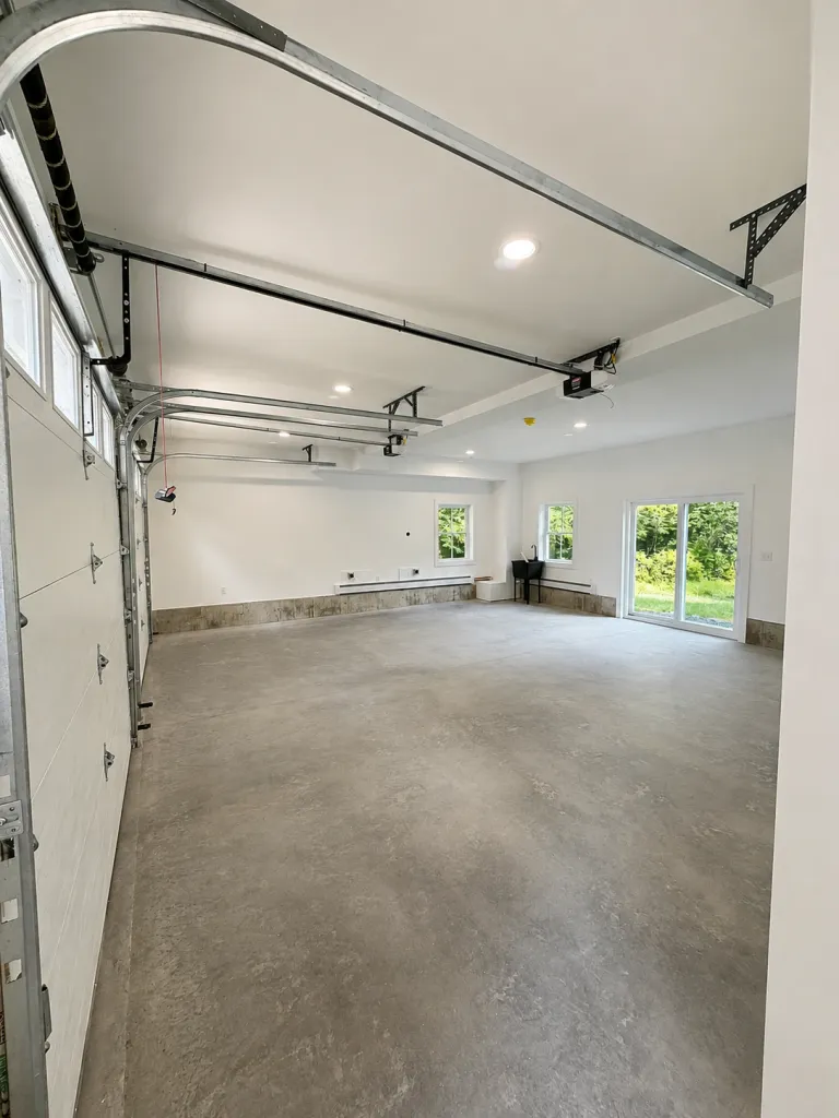 Finished two-car garage interior with overhead doors and recessed lighting in Maine