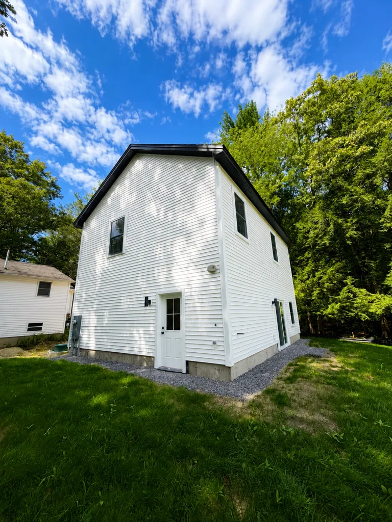 Newly built two-story structure with white vinyl siding in Maine